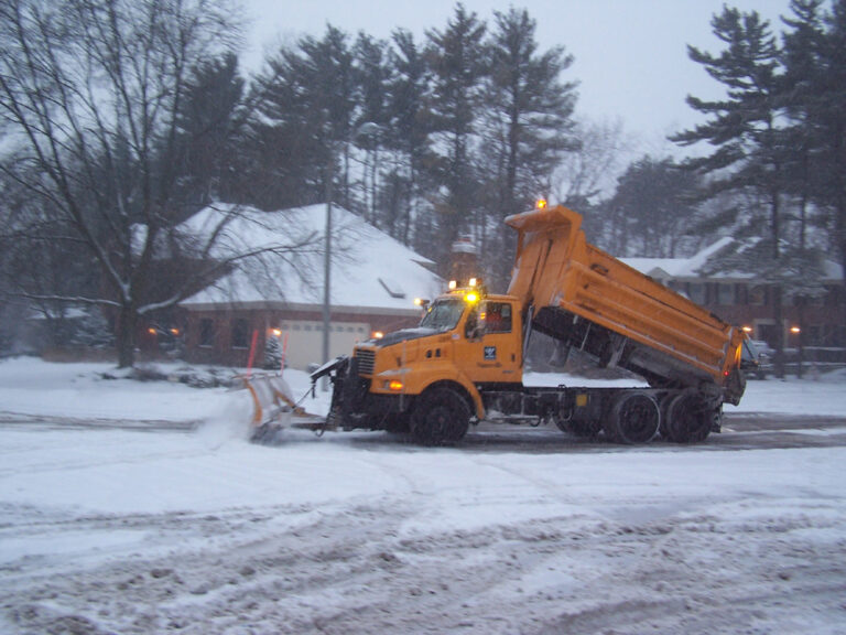 Snow plow clearing snow covered residential street
