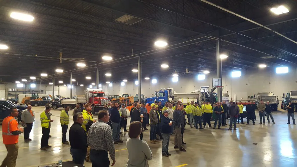 People gathered in warehouse with snow plows for a training